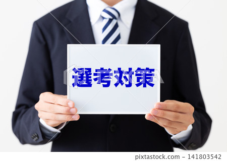 A young businessman in a business suit holding a whiteboard for interview preparation. A young businessman in a business suit holding a whiteboard for interview preparation. 141803542