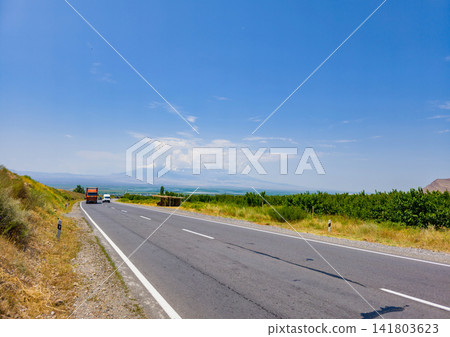 Open road winding through hilly landscape under clear sky Open road winding through hilly landscape under clear sky 141803623