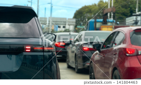 Rear side of SUV car driving on the aspahlt road. Vehicle stuck in the middle of a row of cars on the road Revealing the taillights and the design of the car. Which fits in with the daily commute. Rear side of SUV car driving on the aspahlt road. Vehicle stuck in the middle of a row of cars on the road Revealing the taillights and the design of the car. Which fits in with the daily commute. 141804463