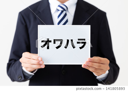一位身穿西裝的年輕商人手持一塊白板,上面寫著「Owahara」(求職騷擾)。 一位身穿西裝的年輕商人手持一塊白板,上面寫著「Owahara」(求職騷擾)。 141805893