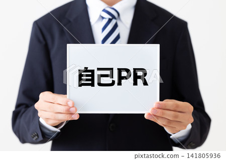 A young businessman in a business suit holding a whiteboard with his self-introduction. A young businessman in a business suit holding a whiteboard with his self-introduction. 141805936