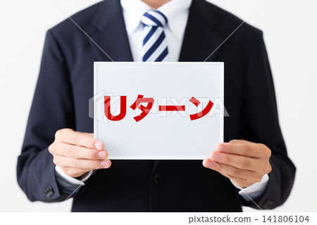 A young businessman in a business suit holding a whiteboard with the word "U-turn" on it. A young businessman in a business suit holding a whiteboard with the word "U-turn" on it. 141806104