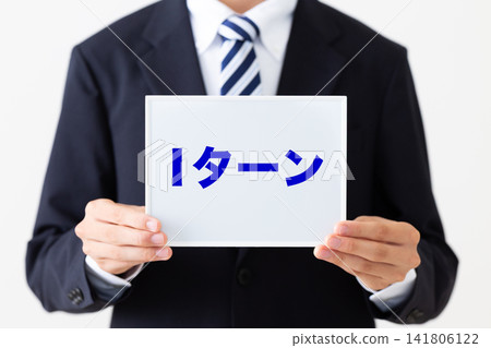 A young businessman in a business suit holding a whiteboard advertising "I-turn" (relocation to a rural area). A young businessman in a business suit holding a whiteboard advertising "I-turn" (relocation to a rural area). 141806122