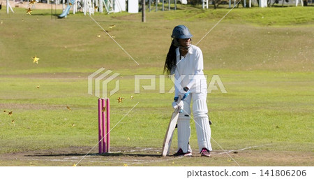 Standing batter wearing navy helmet and pads at park ground, holding wooden bat near pink stumps Standing batter wearing navy helmet and pads at park ground, holding wooden bat near pink stumps 141806206