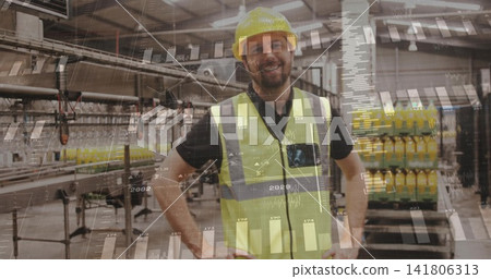 Standing supervisor wearing yellow hard hat, glasses and vest at plant, with conveyors and bottles Standing supervisor wearing yellow hard hat, glasses and vest at plant, with conveyors and bottles 141806313