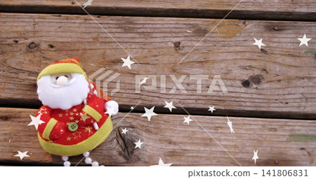 Resting plush Santa doll wearing red coat on worn wooden planks, white stars, copy space Resting plush Santa doll wearing red coat on worn wooden planks, white stars, copy space 141806831