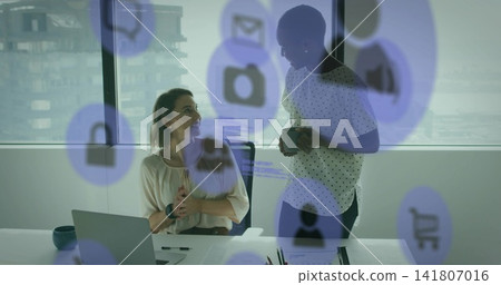 Talking women in business attire reviewing docs at office near window with laptop mugs purple-icons Talking women in business attire reviewing docs at office near window with laptop mugs purple-icons 141807016