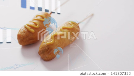 Displaying two corn dogs on wooden skewers with mustard, studio tabletop with blue data overlays Displaying two corn dogs on wooden skewers with mustard, studio tabletop with blue data overlays 141807333