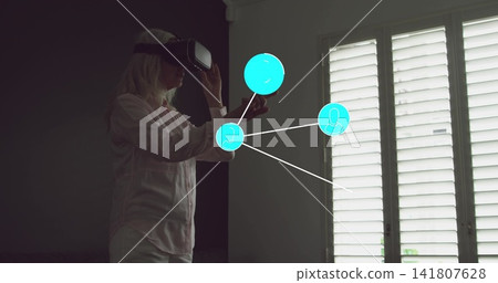 Interacting woman wearing VR headset, pale shirt and light pants, using cyan node interface at home Interacting woman wearing VR headset, pale shirt and light pants, using cyan node interface at home 141807628