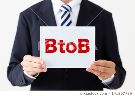 A young businessman in a business suit holding a B2B whiteboard. A young businessman in a business suit holding a B2B whiteboard. 141807789