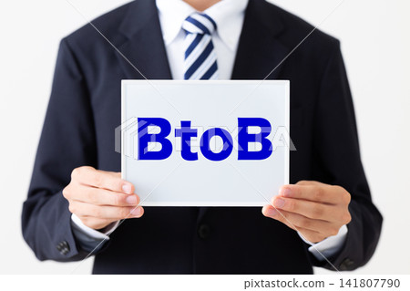A young businessman in a business suit holding a B2B whiteboard. A young businessman in a business suit holding a B2B whiteboard. 141807790