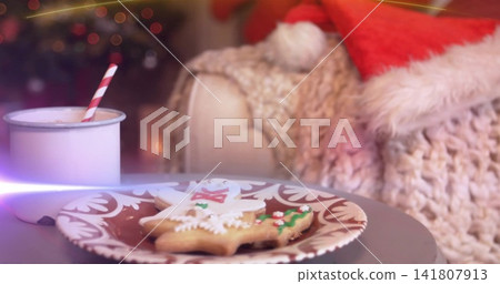 Displaying plate holding iced cookies on small round table at home, with enamel mug, Santa hat 141807913