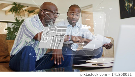 Reviewing two men wearing button-up shirts and jeans on sofa at home, studying laptop map TRACK 141808051