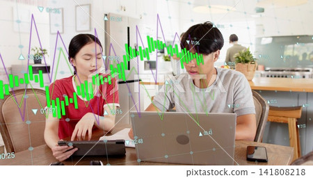 Talking couple in casual clothes using tablet and laptop at kitchen table, stock charts overlay Talking couple in casual clothes using tablet and laptop at kitchen table, stock charts overlay 141808218