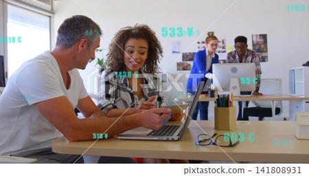 Working team in white tee, checked shirt leaning over laptop and phone at office, teal graphics 141808931