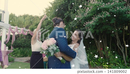Embracing bride in wedding gown with veil and partner in navy suit, holding bouquet in garden Embracing bride in wedding gown with veil and partner in navy suit, holding bouquet in garden 141809002