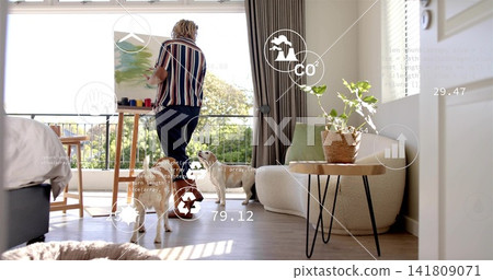 Painting woman artist wearing striped shirt and dark trousers in living room with easel, dogs, AR 141809071