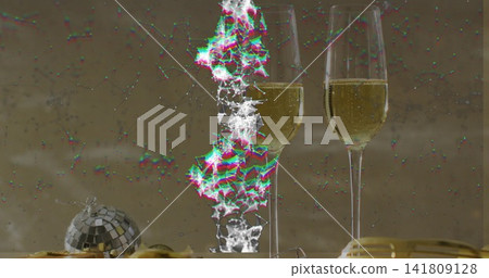 Displaying two champagne flutes fizzing on shiny table with disco ball, gold ribbon, particle mesh 141809128