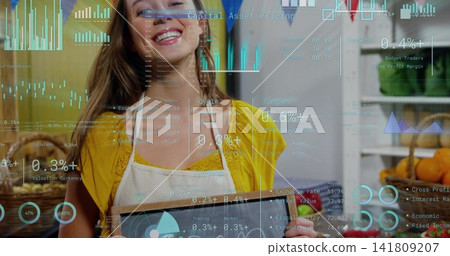 Holding sign, clerk wearing yellow top, white apron working in bakery amid baskets, data overlay 141809207