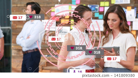 Discussing, two women in white tops holding tablet at office with Post-it board heart icons Discussing, two women in white tops holding tablet at office with Post-it board heart icons 141809380
