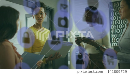 Discussing four coworkers in yellow top holding laptop tablet notes in office with digital icons Discussing four coworkers in yellow top holding laptop tablet notes in office with digital icons 141809729