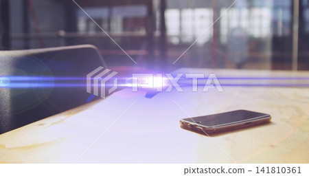 Resting smartphone on worn wood table in office, with long flare, windows, chair left, copy space Resting smartphone on worn wood table in office, with long flare, windows, chair left, copy space 141810361