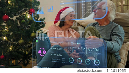Sharing senior couple viewing AR overlays on couch at home, with Christmas tree, Santa hat Sharing senior couple viewing AR overlays on couch at home, with Christmas tree, Santa hat 141811065