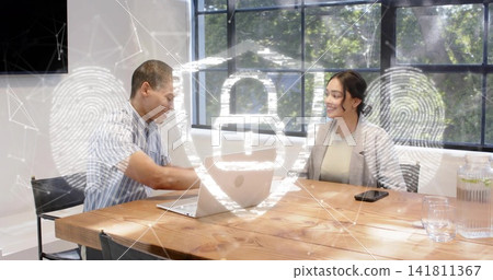 Discussing coworkers at office table, wearing striped shirt and blazer, with laptop, security icons Discussing coworkers at office table, wearing striped shirt and blazer, with laptop, security icons 141811367