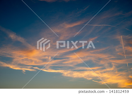 A breathtaking sky during sunrise or sunset featuring delicate wispy clouds illuminated by warm golden light A breathtaking sky during sunrise or sunset featuring delicate wispy clouds illuminated by warm golden light 141812459