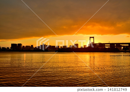 A sunset view of the Rainbow Bridge shrouded in thick clouds, as seen from Odaiba Seaside Park. 141812749