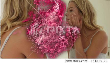 Touching cheek, adult woman checking bathroom mirror, wearing gray strappy top, pink cloud overlay Touching cheek, adult woman checking bathroom mirror, wearing gray strappy top, pink cloud overlay 141813122