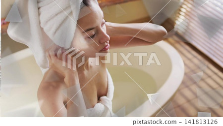 Adjusting mid-adult woman fixing white turban and body towel in oval tub, blinds, overlays Adjusting mid-adult woman fixing white turban and body towel in oval tub, blinds, overlays 141813126