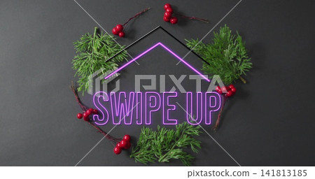 Glowing neon SWIPE UP sign with arrow outline on dark tabletop, pine sprigs and red berries Glowing neon SWIPE UP sign with arrow outline on dark tabletop, pine sprigs and red berries 141813185