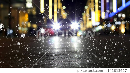 Falling snowflakes and wet pavement creating headlight glare on nighttime city street, with lights 141813627