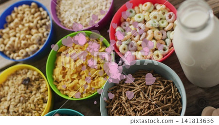 Showing array of bright cereal bowls filling wooden kitchen table, with milk jar and pink hearts Showing array of bright cereal bowls filling wooden kitchen table, with milk jar and pink hearts 141813636