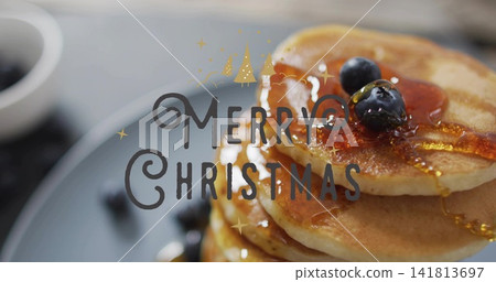 Showing pancake stack shining on tabletop with blueberries, maple syrup, Merry Christmas overlay Showing pancake stack shining on tabletop with blueberries, maple syrup, Merry Christmas overlay 141813697