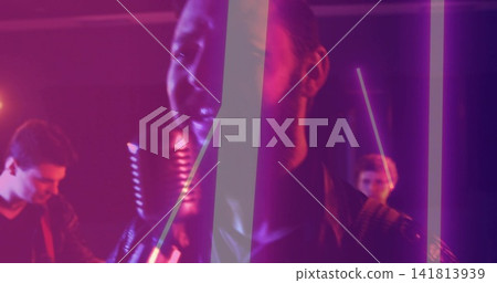 Singing lead vocalist leaning into vintage ribbon microphone on club stage, wearing leather jacket 141813939