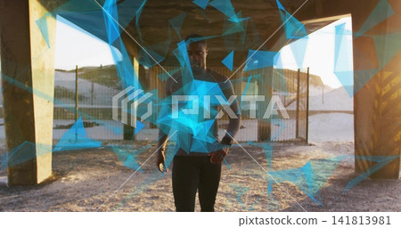 Standing man wearing dark tights under concrete pillars at shoreline, showing watch and AR overlays 141813981