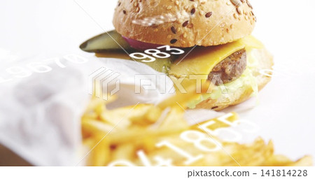 Showcasing burger on white table with sesame bun, melted cheese, pickle, blurry fries, numeric text Showcasing burger on white table with sesame bun, melted cheese, pickle, blurry fries, numeric text 141814228