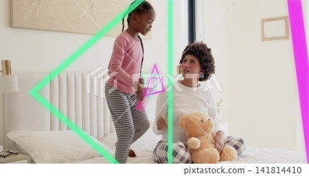 Playing mom-daughter sitting on bed wearing pjs and striped leggings holding teddy, neon overlays Playing mom-daughter sitting on bed wearing pjs and striped leggings holding teddy, neon overlays 141814410