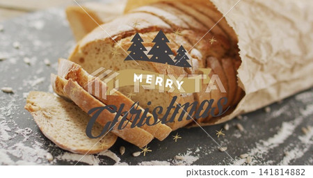 Showing sliced rustic loaf on dark floured slate with parchment and Merry Christmas graphic Showing sliced rustic loaf on dark floured slate with parchment and Merry Christmas graphic 141814882