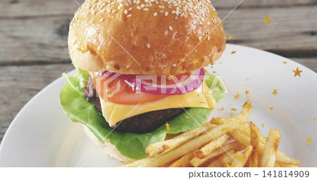 Displaying stacked burger with sesame bun, cheddar and fries on ceramic plate, gold stars Displaying stacked burger with sesame bun, cheddar and fries on ceramic plate, gold stars 141814909