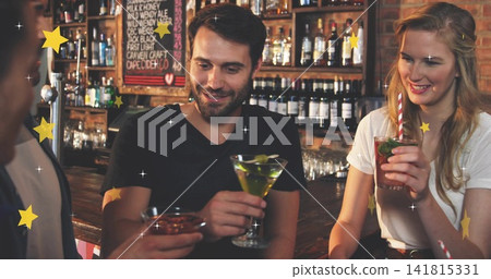Smiling bearded man holding martini with lime at wooden bar counter, with mint highball and lowball Smiling bearded man holding martini with lime at wooden bar counter, with mint highball and lowball 141815331