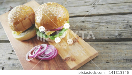 Displaying two sesame brioche sliders resting with cheese lettuce onion on board, speech bubbles Displaying two sesame brioche sliders resting with cheese lettuce onion on board, speech bubbles 141815546