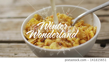 Pouring milk splashing cornflakes in bowl on wooden table, with spoon, Winter Wonderland overlay Pouring milk splashing cornflakes in bowl on wooden table, with spoon, Winter Wonderland overlay 141815651