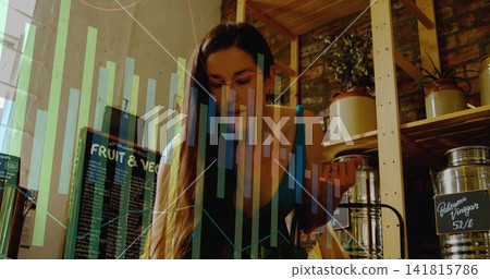 Leaning woman in sleeveless blue top examining product at bulk shop, with chalkboard and charts Leaning woman in sleeveless blue top examining product at bulk shop, with chalkboard and charts 141815786