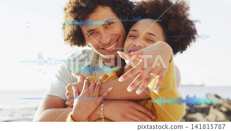 Smiling adult couple embracing at rocky shoreline, showing ring, mustard sweater, waveform overlay Smiling adult couple embracing at rocky shoreline, showing ring, mustard sweater, waveform overlay 141815787