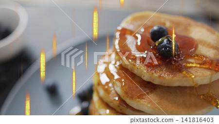 Pouring maple syrup over stack of golden pancakes on matte gray plate on tabletop, with blueberries Pouring maple syrup over stack of golden pancakes on matte gray plate on tabletop, with blueberries 141816403