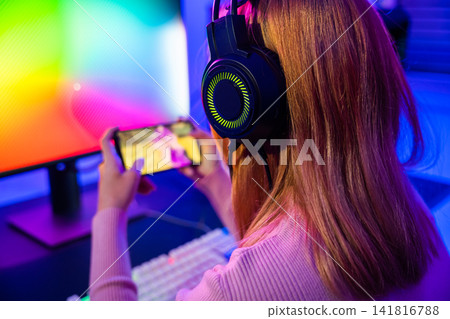 Asian woman live stream she play video game via smartphone at home neon lights living room Asian woman live stream she play video game via smartphone at home neon lights living room 141816788