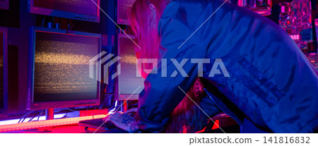 Asian woman wearing a black jacket hacking programming system and working with computer monitor display in dark office, Cyber security agency developing website cyber security Asian woman wearing a black jacket hacking programming system and working with computer monitor display in dark office, Cyber security agency developing website cyber security 141816832